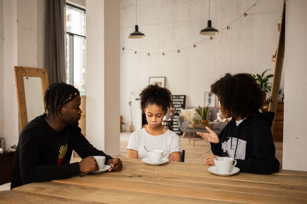 black parents lecturing upset daughter at table
